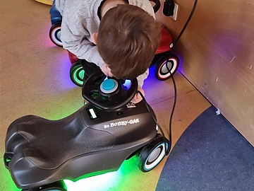 Ein Kind schließt das Bobby-Car an die Ladestation